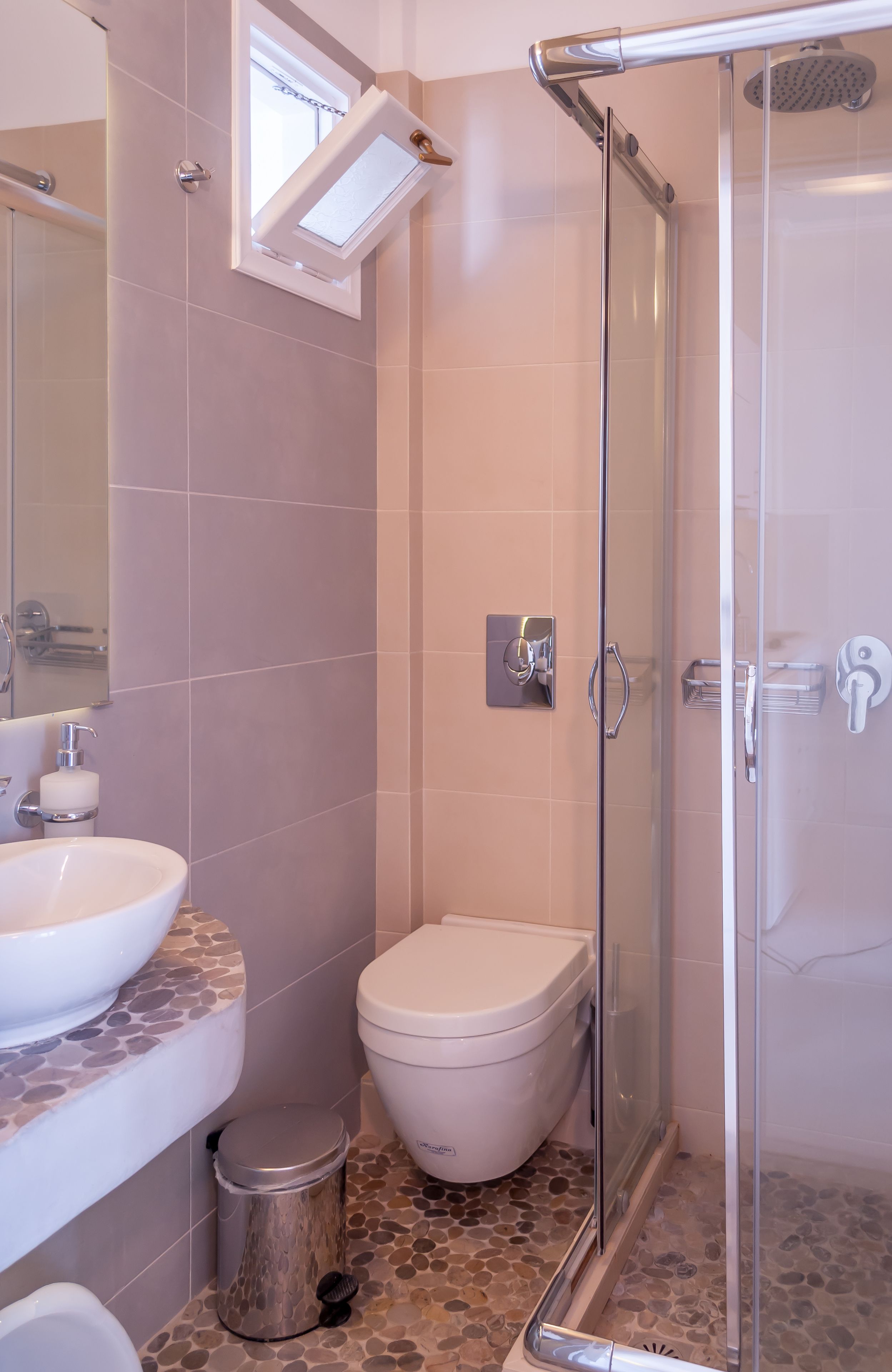 Un baño con ducha de vidrio, inodoro e lavamanos con encimera de azulejos.