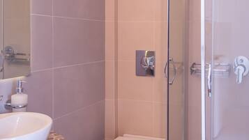 Un baño con ducha de vidrio, inodoro e lavamanos con encimera de azulejos.