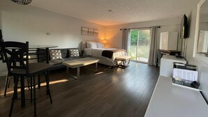 Una habitación moderna con una cama, un sofá, una mesa de comedor y un televisor.