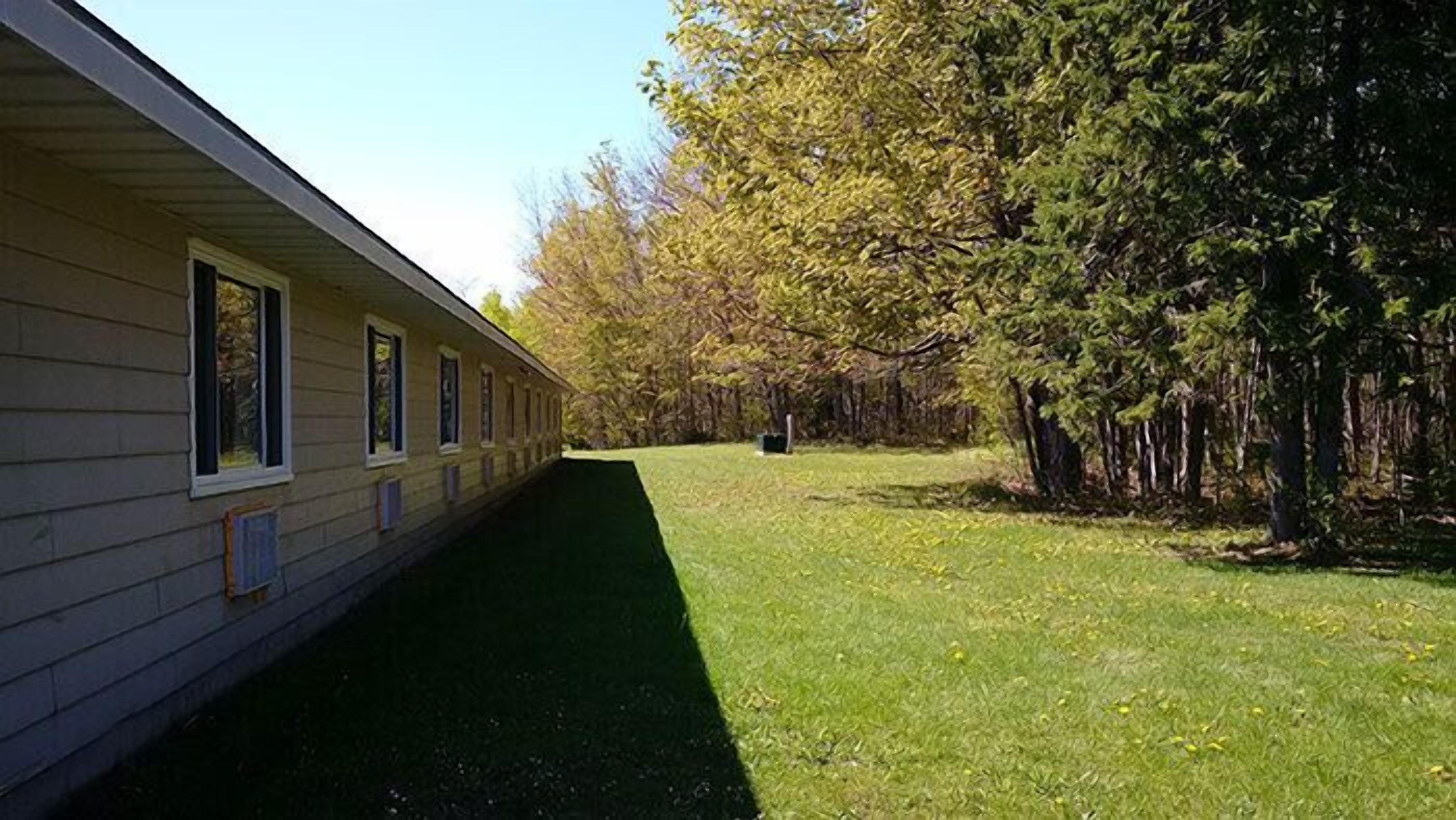 Une rangée de chalets de plain-pied, avec une pelouse et des arbres en arrière-plan.