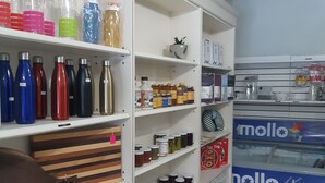 Una despensa bien organizada con estantes llenos de diversos alimentos, incluyendo frascos de conservas y botellas de salsas.
