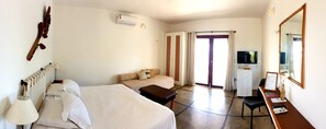 A hotel room with two beds, a desk with a computer, a TV, and a minibar. - Amagali Pousada (Galinhos)
