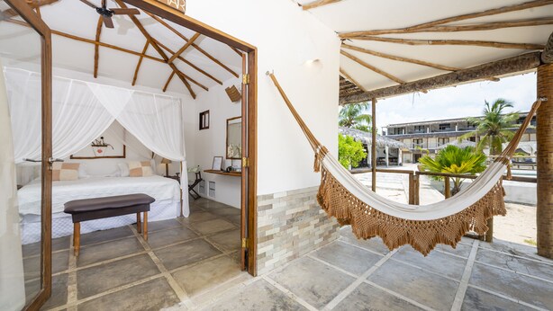 Una habitació amb llit, una panxa, un hamaca i vistes cap a l'exterior.