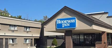 A Rodeway Inn building with a prominent sign, a covered entrance, and a parking lot.