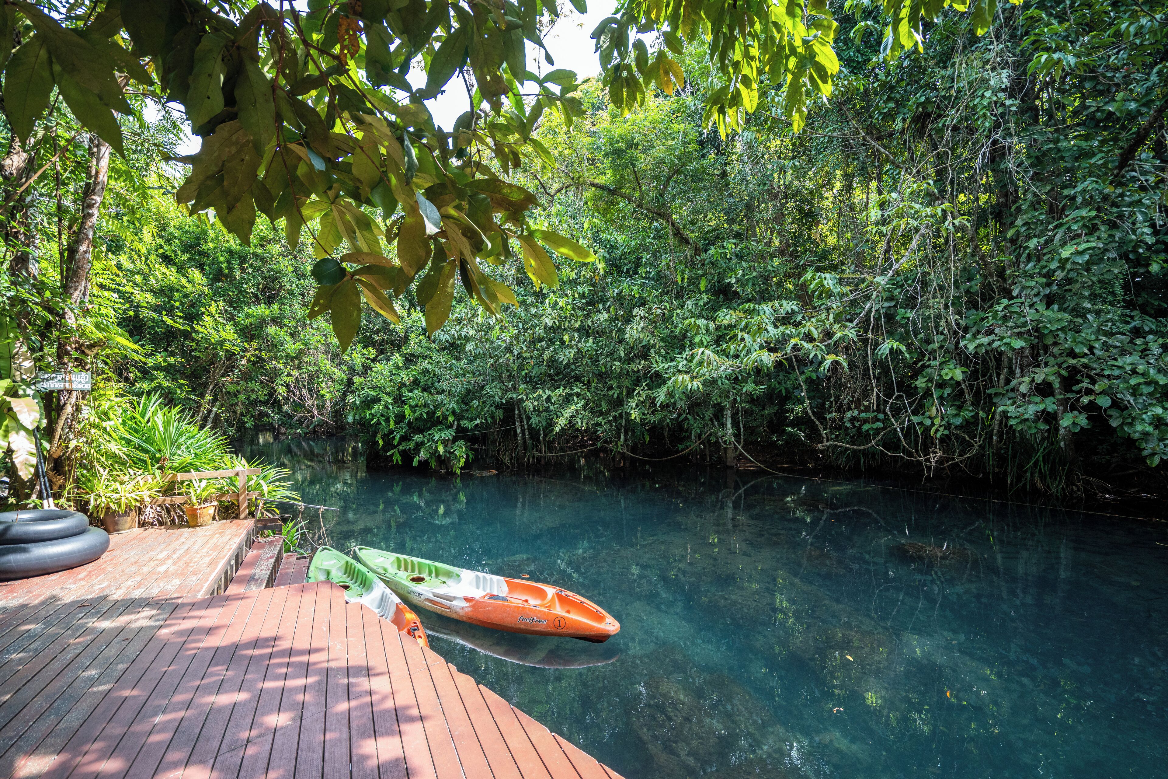 A wooden dock with a clear waterway and a green kayak.