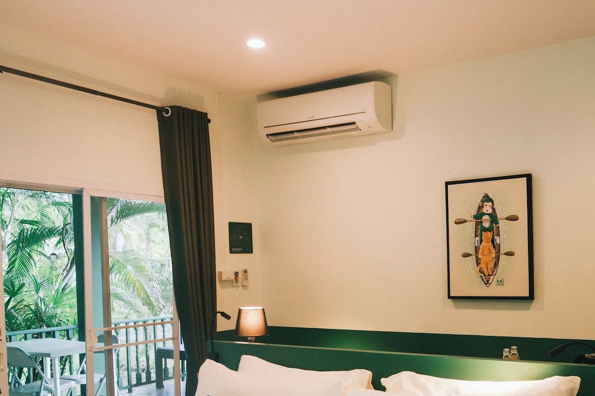 Une chambre d’hôtel avec un lit, un tableau au mur, un climatiseur et une vue sur l’extérieur.
