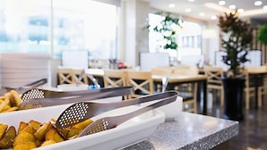 A buffet area with a white serving tray containing roasted potatoes and tongs.
