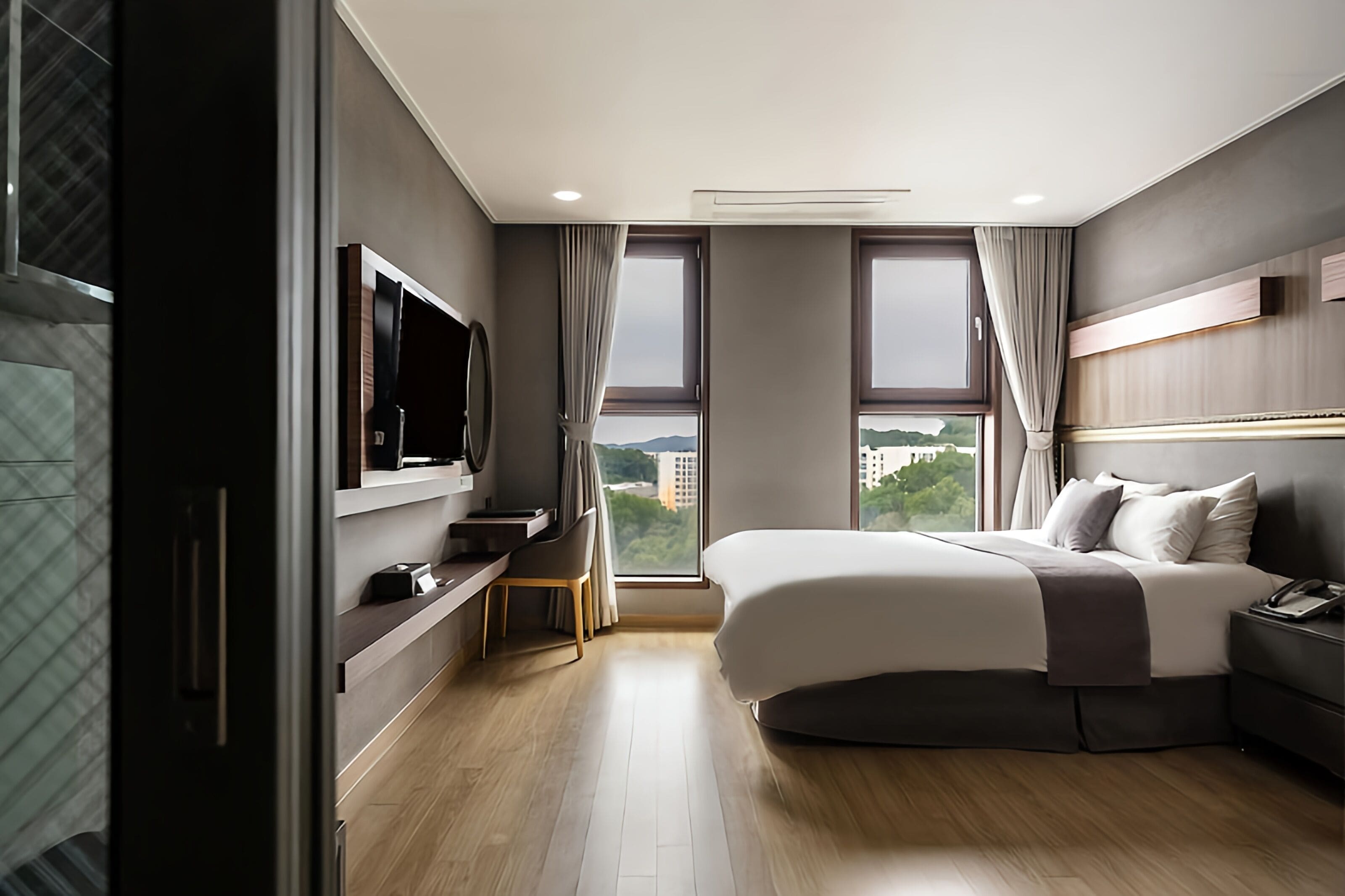 Een moderne hotelkamer met een groot bed, een bureau, een flatscreen-tv en uitzicht op de stad.