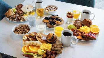 Una mesa blanca con una variedad de platos, bebidas y frutas para el desayuno.