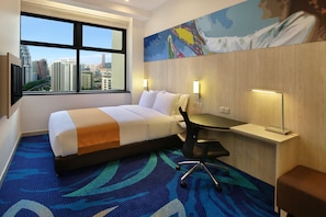 A hotel room with a bed, desk, chair, and a large window offering a city view.