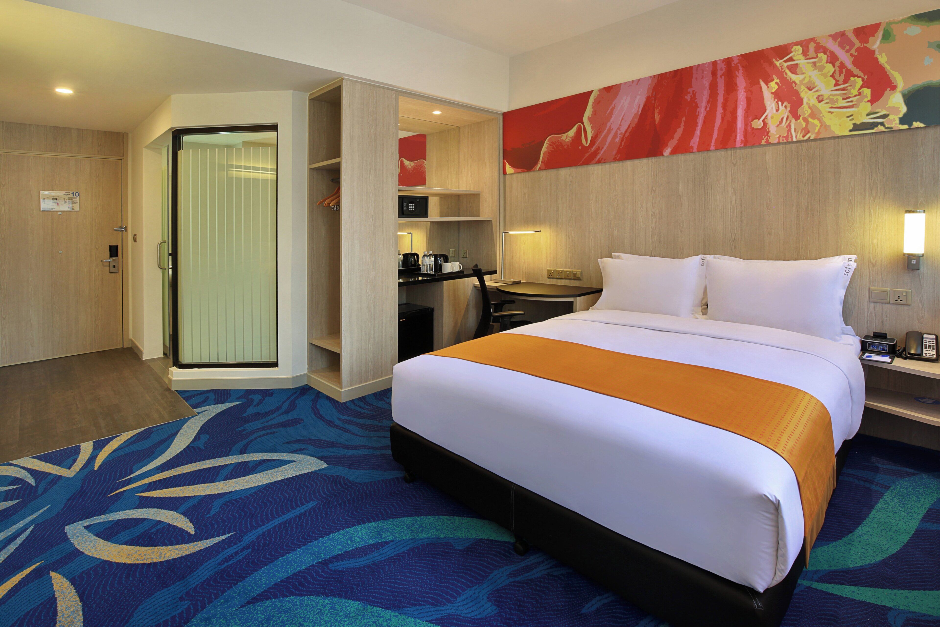 A hotel room with a bed, a desk, a chair, a coffee machine, and a microwave.