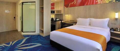 A hotel room with a bed, a desk, a chair, a coffee machine, and a microwave.