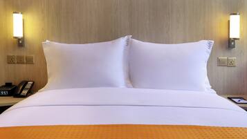 A hotel room with a neatly made bed, two bedside lamps, a bedside phone, and a tablet on the nightstand.
