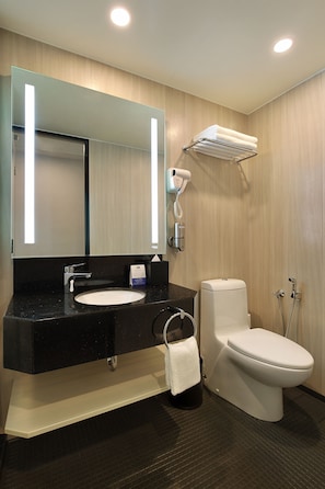 A modern bathroom with a black sink, white toilet, and a hairdryer mounted on the wall.