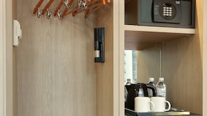 A walk-in closet with wooden shelves, a black refrigerator, a microwave, and a coffee maker.