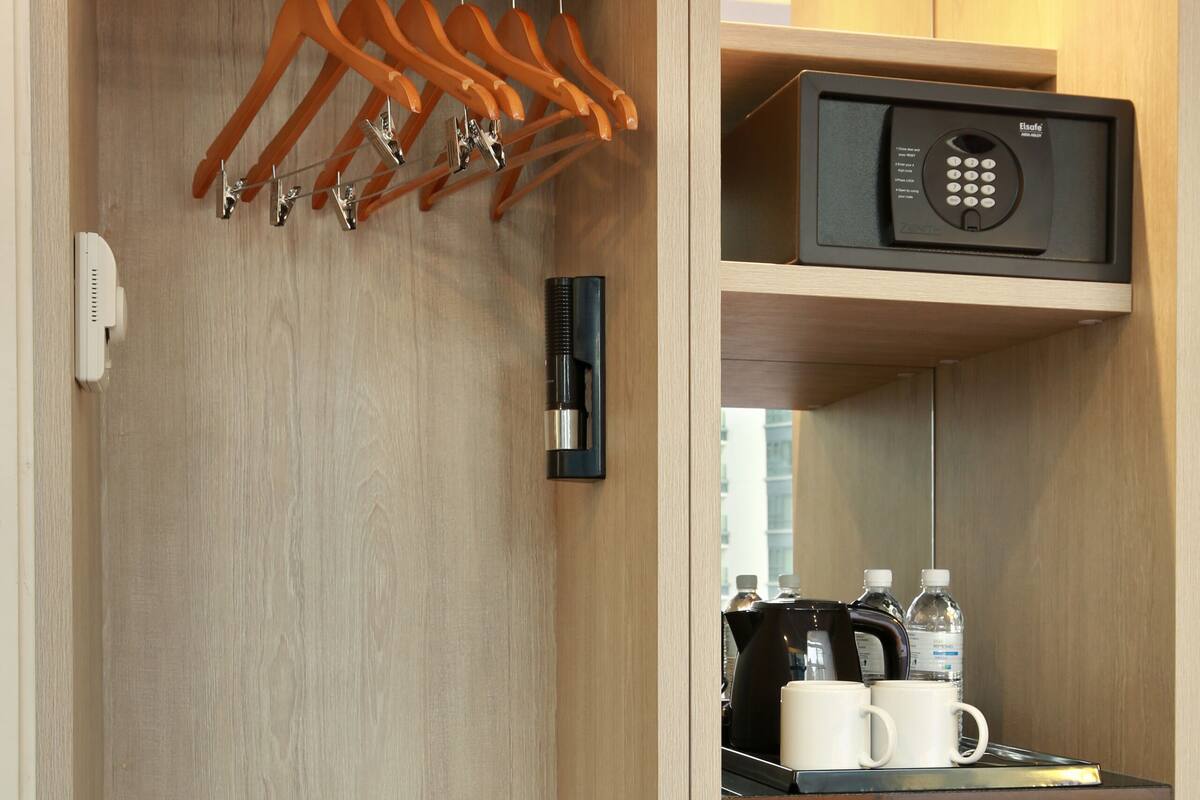 A walk-in closet with wooden shelves, a black refrigerator, a microwave, and a coffee maker.