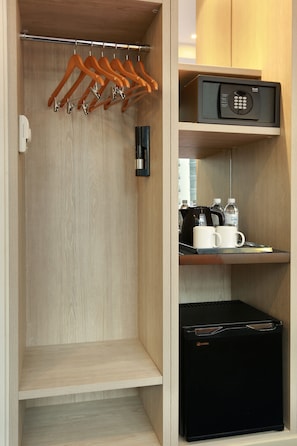 Un closet amplio con repisas de madera, un refrigerador negro, un microondas y una cafetera.