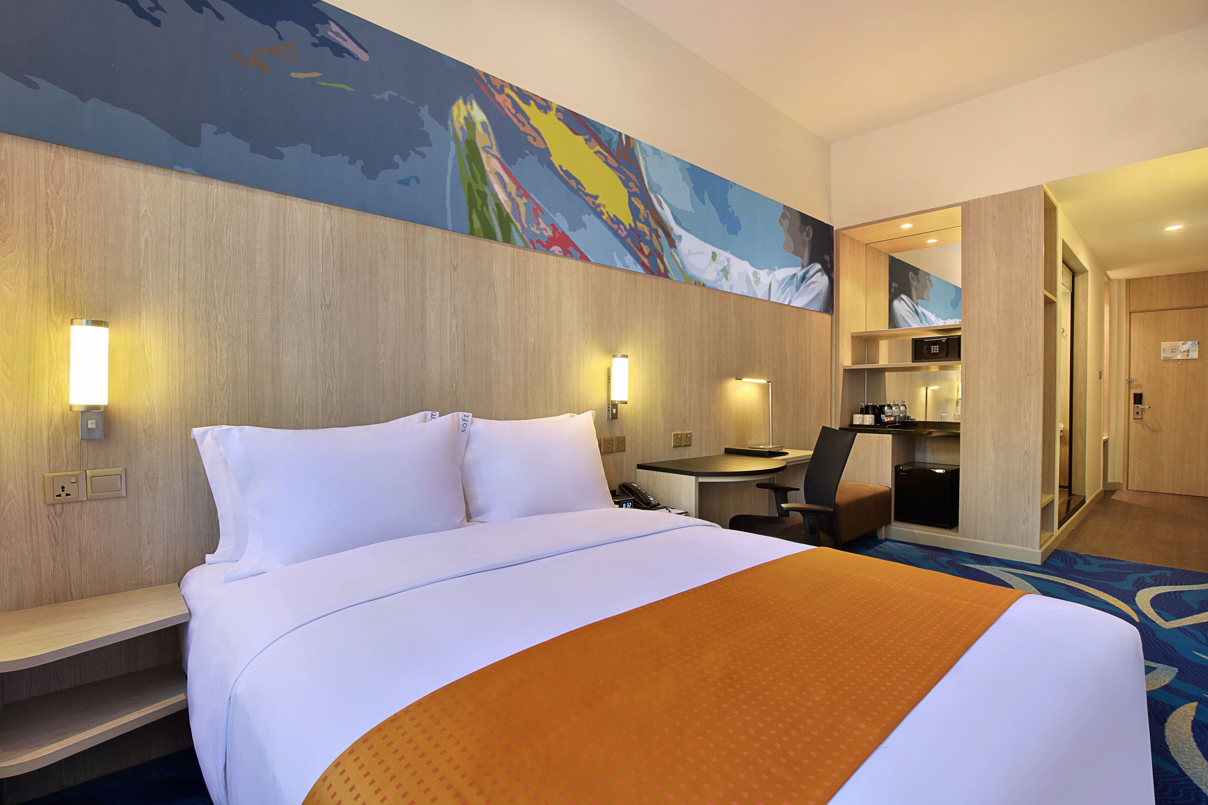 A hotel room with a large bed, a desk, and a microwave.