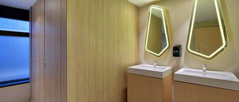 Un baño moderno con armarios de madera, dos lavamanos y espejos iluminados.