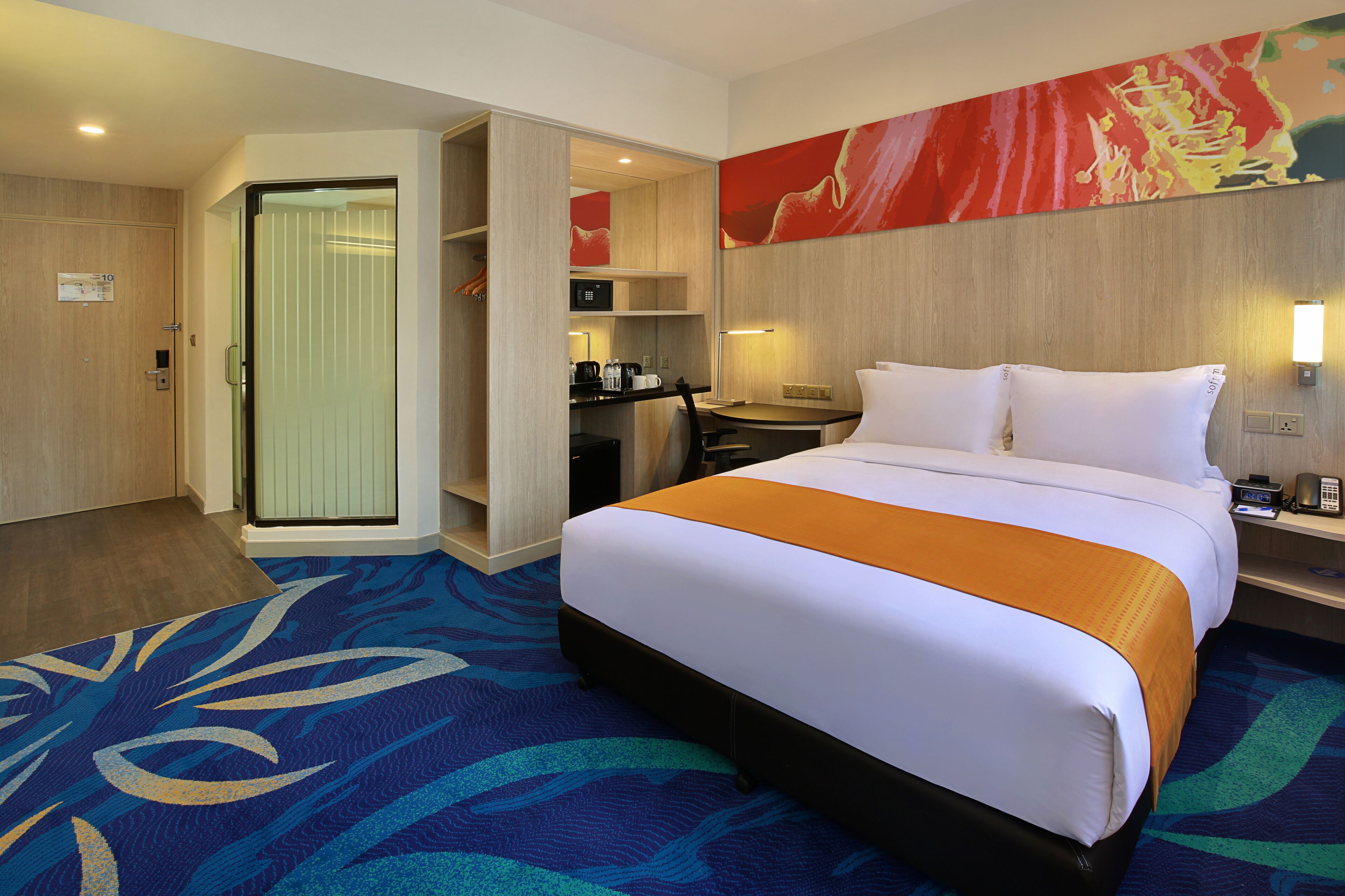 A hotel room with a bed, a desk, a chair, a coffee maker, and a television.