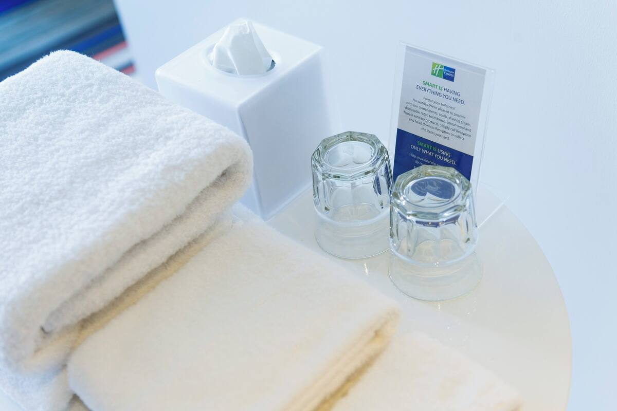 A neatly arranged bathroom with a white towel, a tissue box, and a glass container, likely for toiletries.
