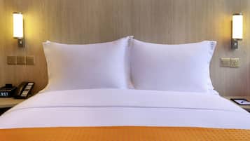 A hotel room with a neatly made bed, two bedside lamps, a bedside phone, and a tablet on the nightstand.