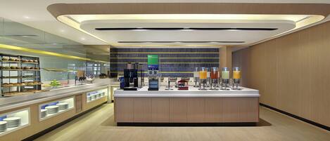 A modern cafe with a central island, counter, and various food and drink options.