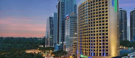 A high-rise hotel with a prominent 'Holiday Inn Express' sign, surrounded by other tall buildings and a busy street with traffic lights.