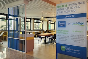 Un área de desayuno con un cartel que anuncia opciones de desayuno gratuito, incluyendo Express Start y Grab & Go.