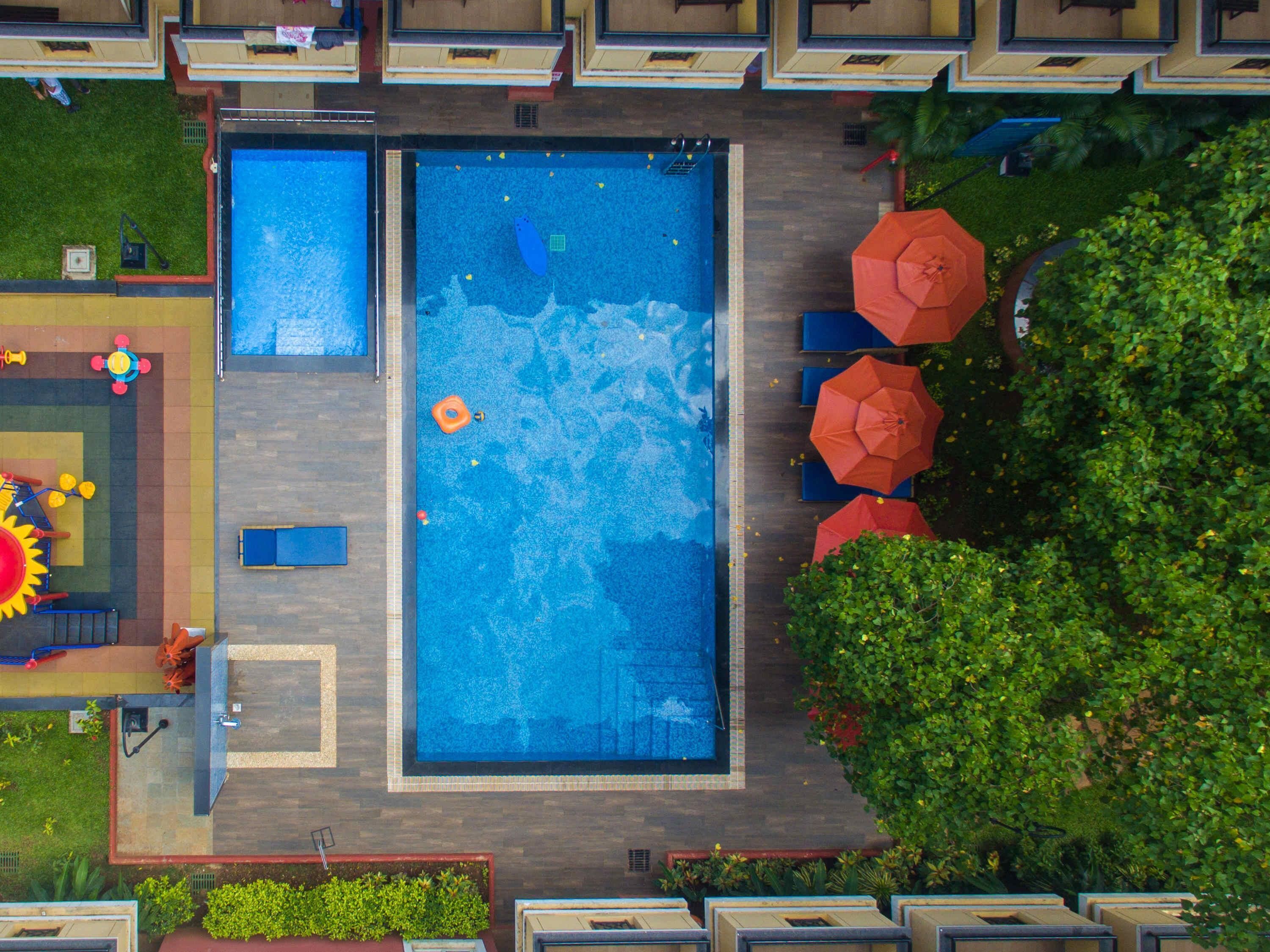 A rooftop swimming pool with a diving board, lounge chairs, and umbrellas.