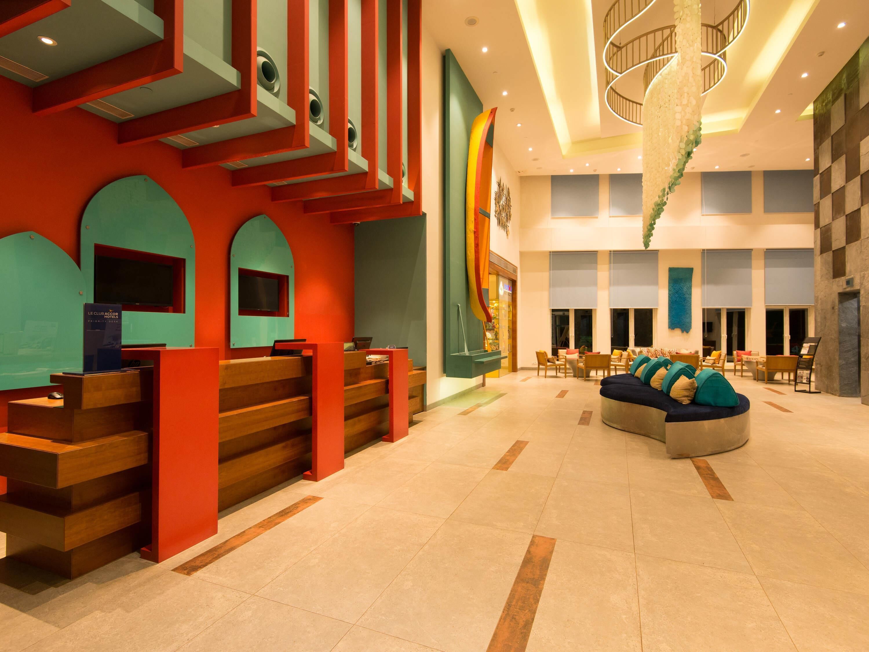 Un hall de hotel con mostrador de recepción, zona de estar y una escalera.