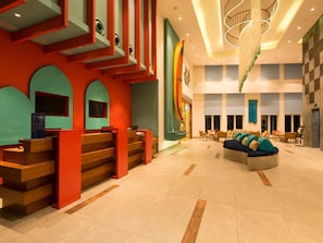 A hotel lobby with a reception desk, seating area, and a staircase. - ibis Styles Goa Calangute Hotel (Calangute)