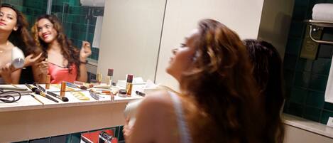 A bathroom with a mirror, toiletries, and a towel rack.
