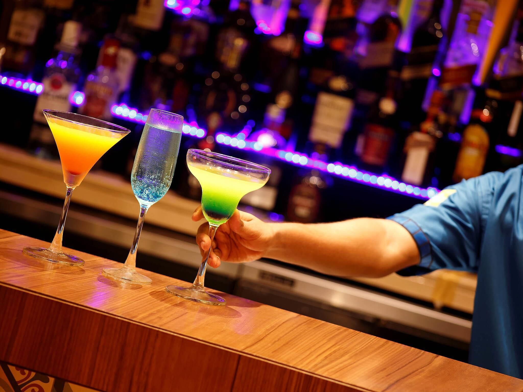 Un bar con tres cócteles coloridos en copas de martini.