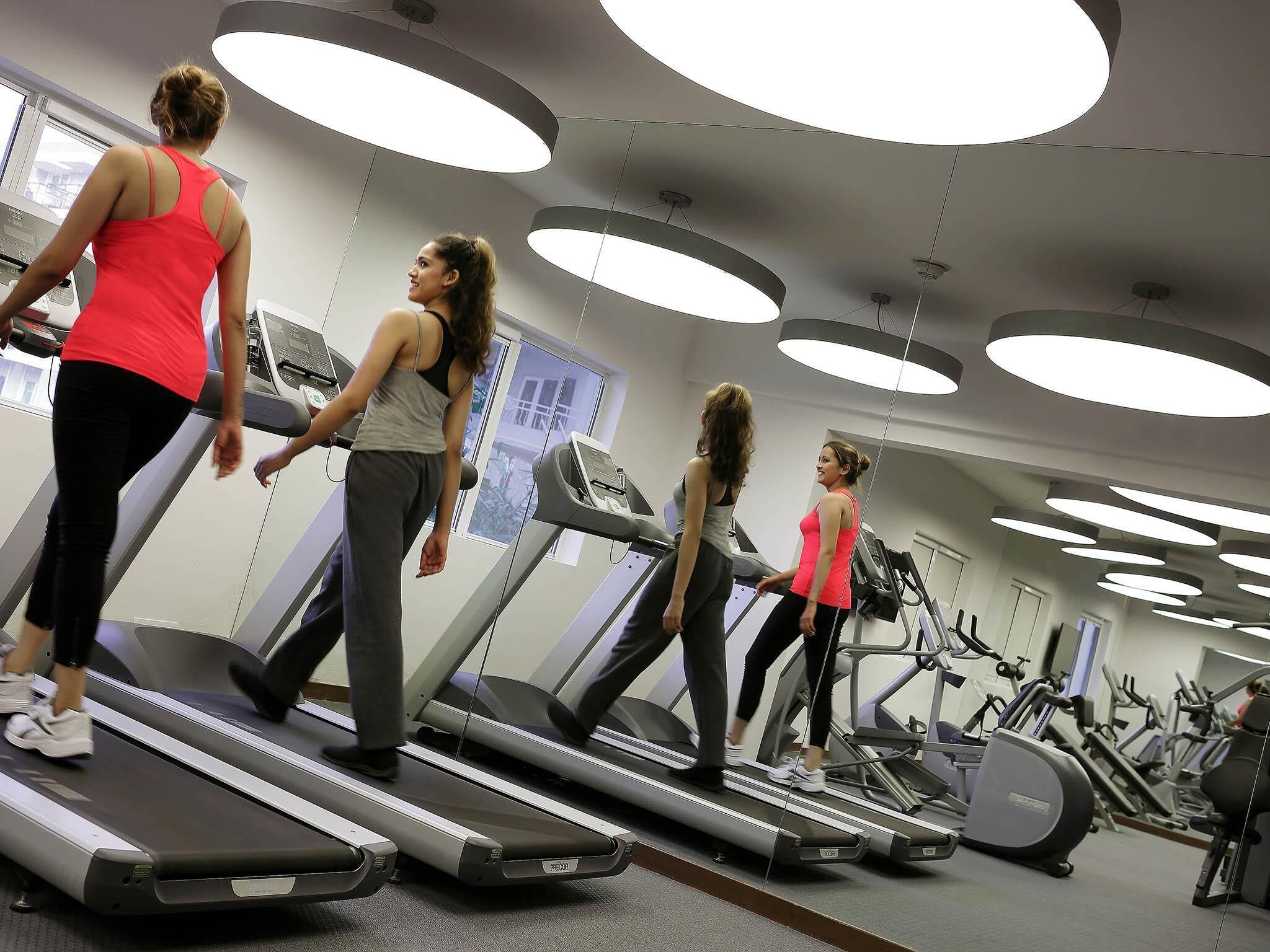 A gym with treadmills, exercise equipment, and large windows.