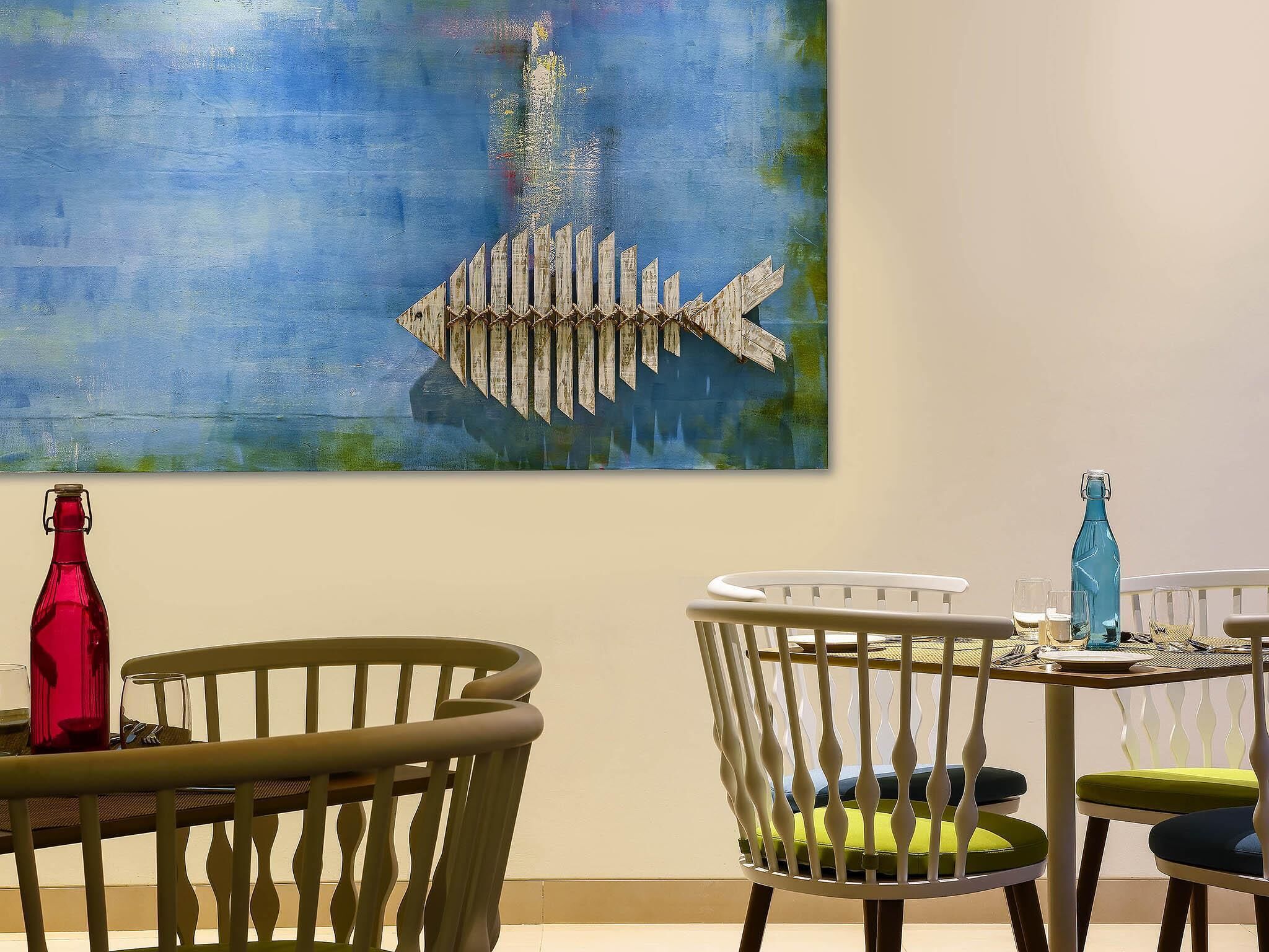 A dining area with a table set for two, featuring a blue bottle and a red bottle on the table.