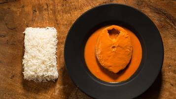 Un plato de arroz blanco y un bol de curry naranja sobre una mesa de madera.