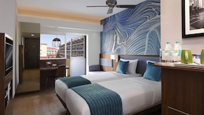 Une chambre d’hôtel avec un grand lit, un bureau et une vue sur les immeubles.
