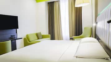A hotel room with a bed, a TV, a desk, and two chairs.