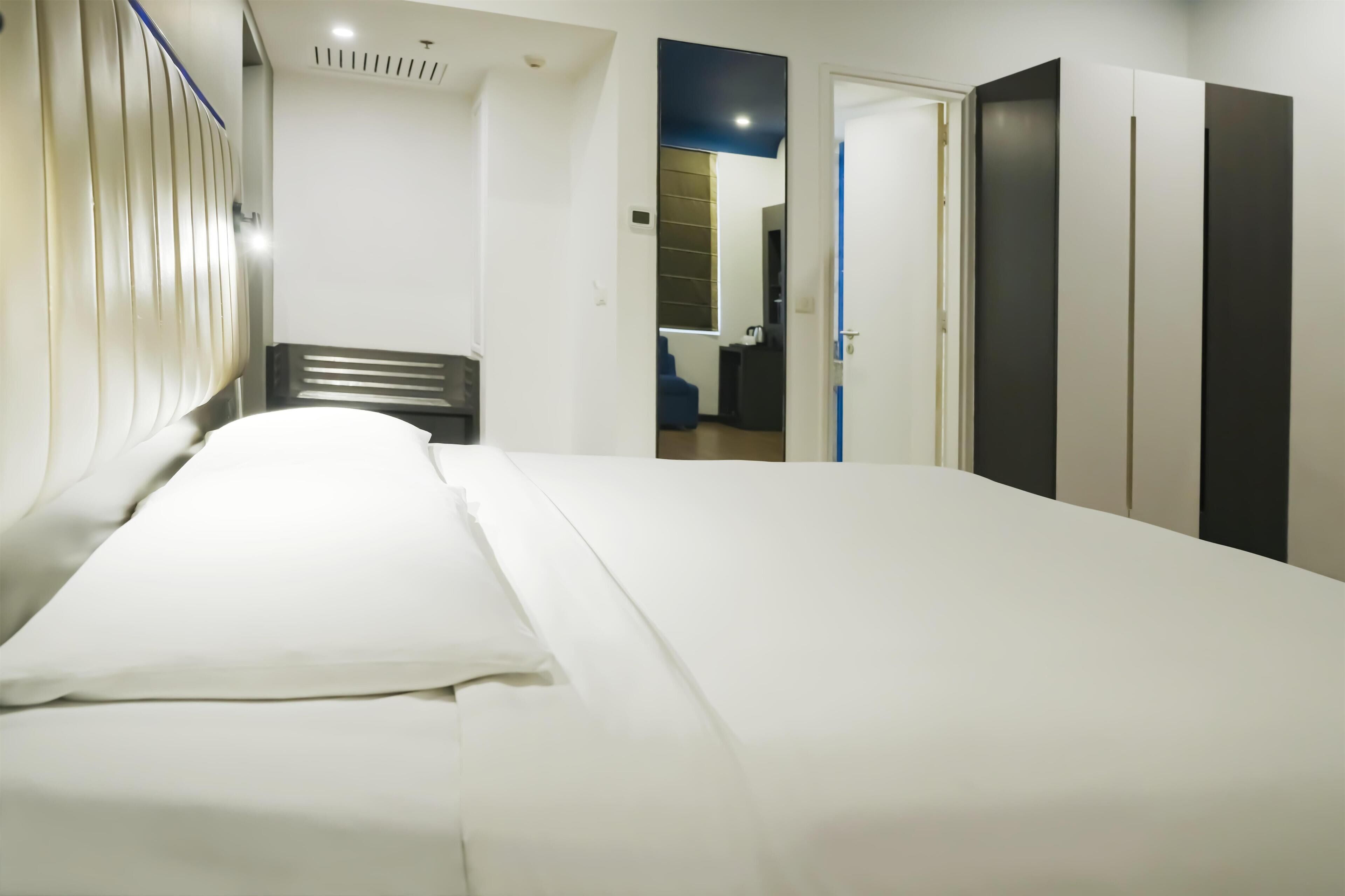 A hotel room with a bed, a bedside table, a wardrobe, and a mirror.