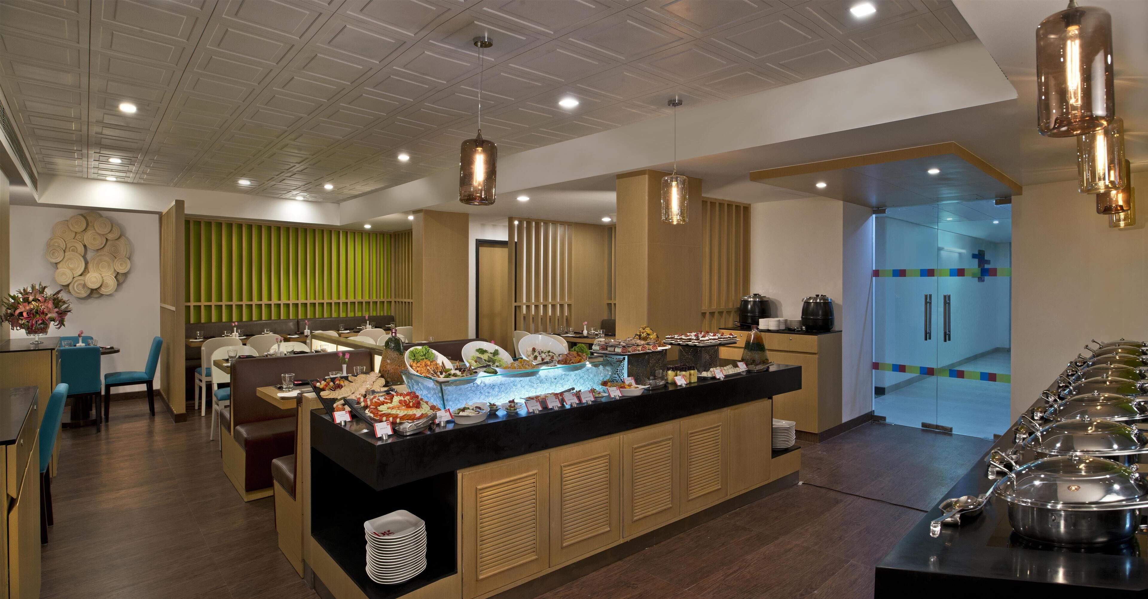 A buffet area with various food items, a seating area with chairs and tables, and a modern ceiling design.