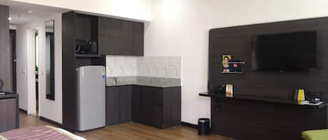 A compact kitchen with dark wood cabinets, a white refrigerator, a microwave, and a black countertop.