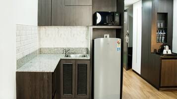 Una cocina moderna con armarios de madera oscura, un refrigerador de acero inoxidable, un microondas y un lavamanos empotrado.