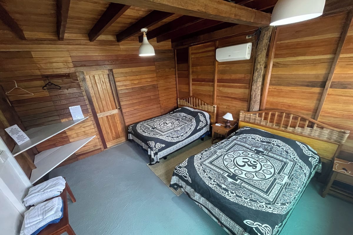 Een houten kamer met twee bedden, een bureau en een kledingrek.