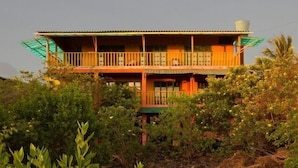 A two-story building with a balcony on the upper floor, surrounded by dense vegetation. - Galapagos Chalet (Puerto Ayora)