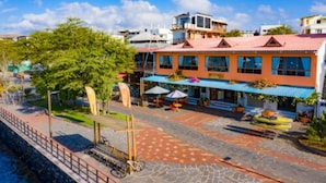 Un hotel con fachada roja y azul, zona de estar al aire libre y patio empedrado.
