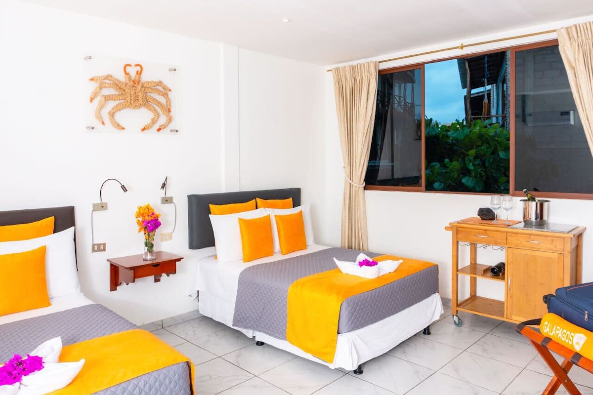 A hotel room with two beds, a desk, and a window with curtains.