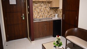 Cocina compacta con armarios de madera, salpicadero de azulejos y una cafetera sobre la encimera.