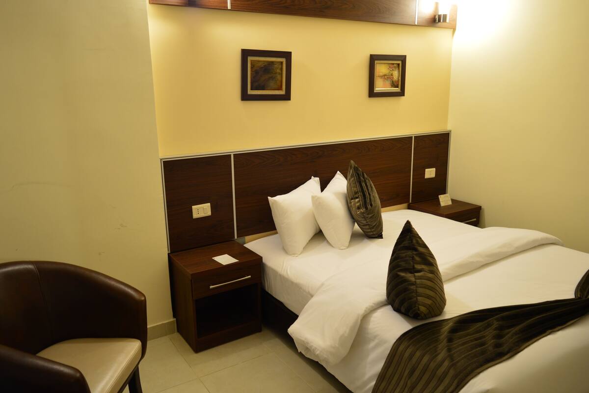A hotel room with a large bed, two nightstands, a wooden headboard, and two framed pictures on the wall.