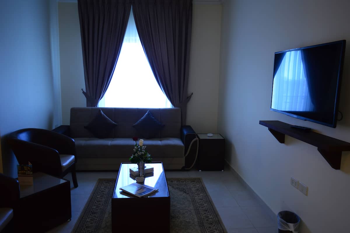 A living room with a sofa, coffee table, TV, and a small plant.